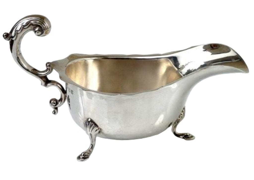 Silver gravy boat with ornate handle on a white background